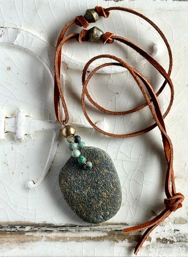 Beach rock with ruff turquoise beads on brown leather.