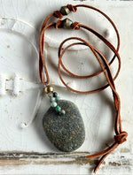 Beach rock with ruff turquoise beads on brown leather.