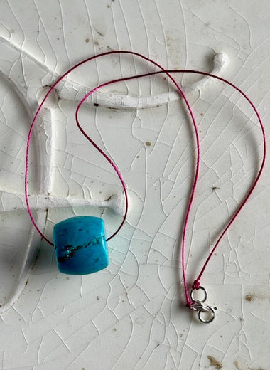 Turquoise barrel bead on magenta cord