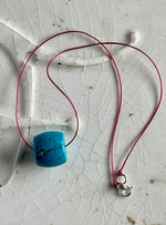 Turquoise barrel bead on magenta cord